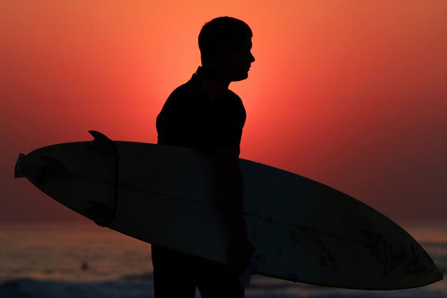 A surfer heads out to catch the early morning waves in Durban