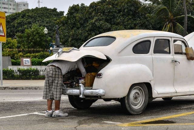 A Cuban attempts to repair his old car in Havana on the day the free sale of cars in Cuba was officially authorized.