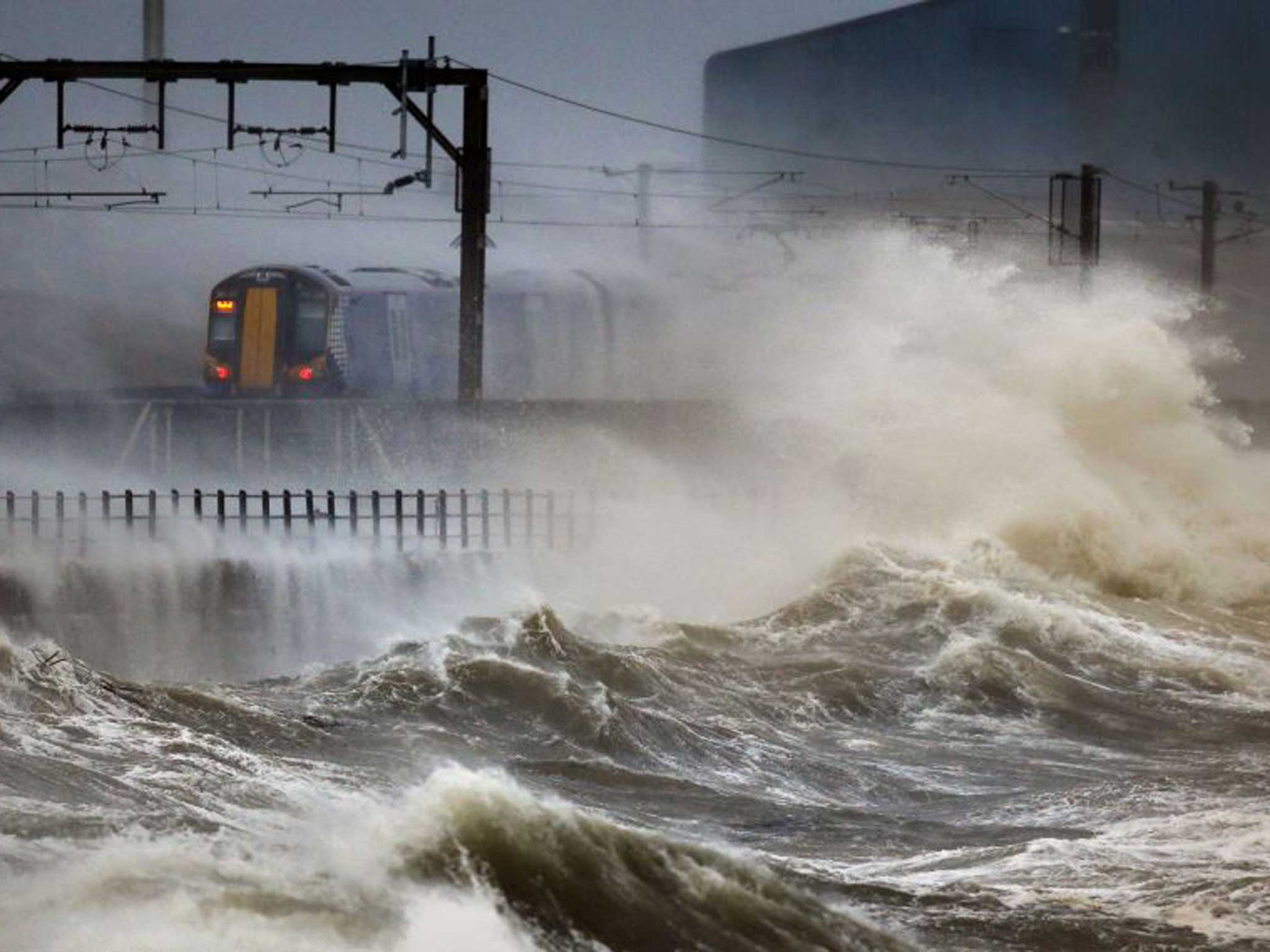 A train passes along the coast at Saltcoats in Scotland, as a combination of high tides, heavy rains and strong winds are expected to bring yet more severe flooding to many parts of the country