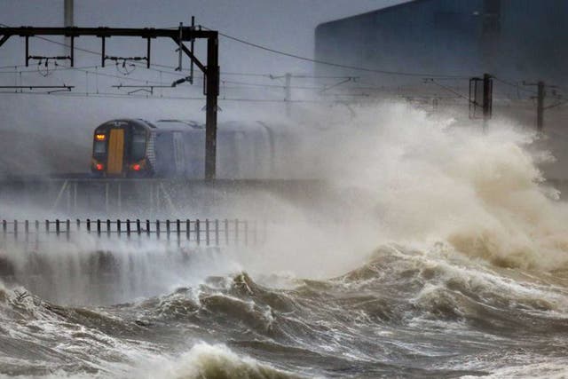 A train passes along the coast at Saltcoats in Scotland, as a combination of high tides, heavy rains and strong winds are expected to bring yet more severe flooding to many parts of the country