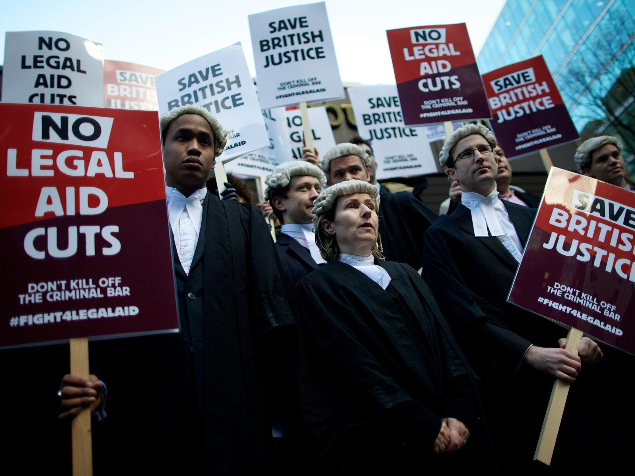 British legal professionals hold placards during a protest against cuts to the legal aid budget during a protest outside Southwark Crown Court
