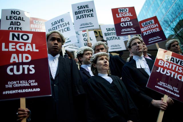 British legal professionals hold placards during a protest against cuts to the legal aid budget during a protest outside Southwark Crown Court 