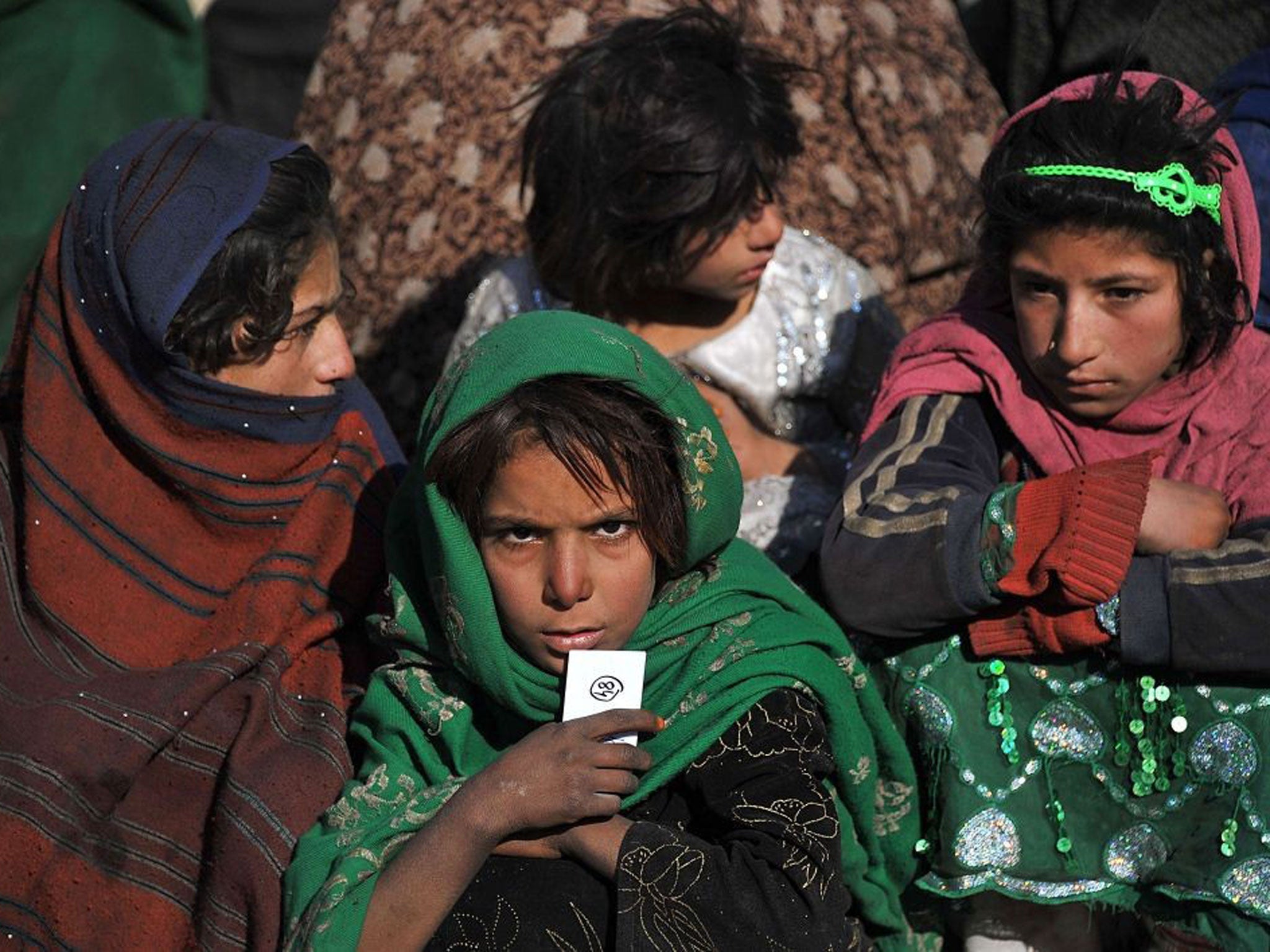 Afghan children wait for relief supplies from the Muslim Hands United For The Needy during an aid distribution at a refugee camp on the outskirts of Kabul
