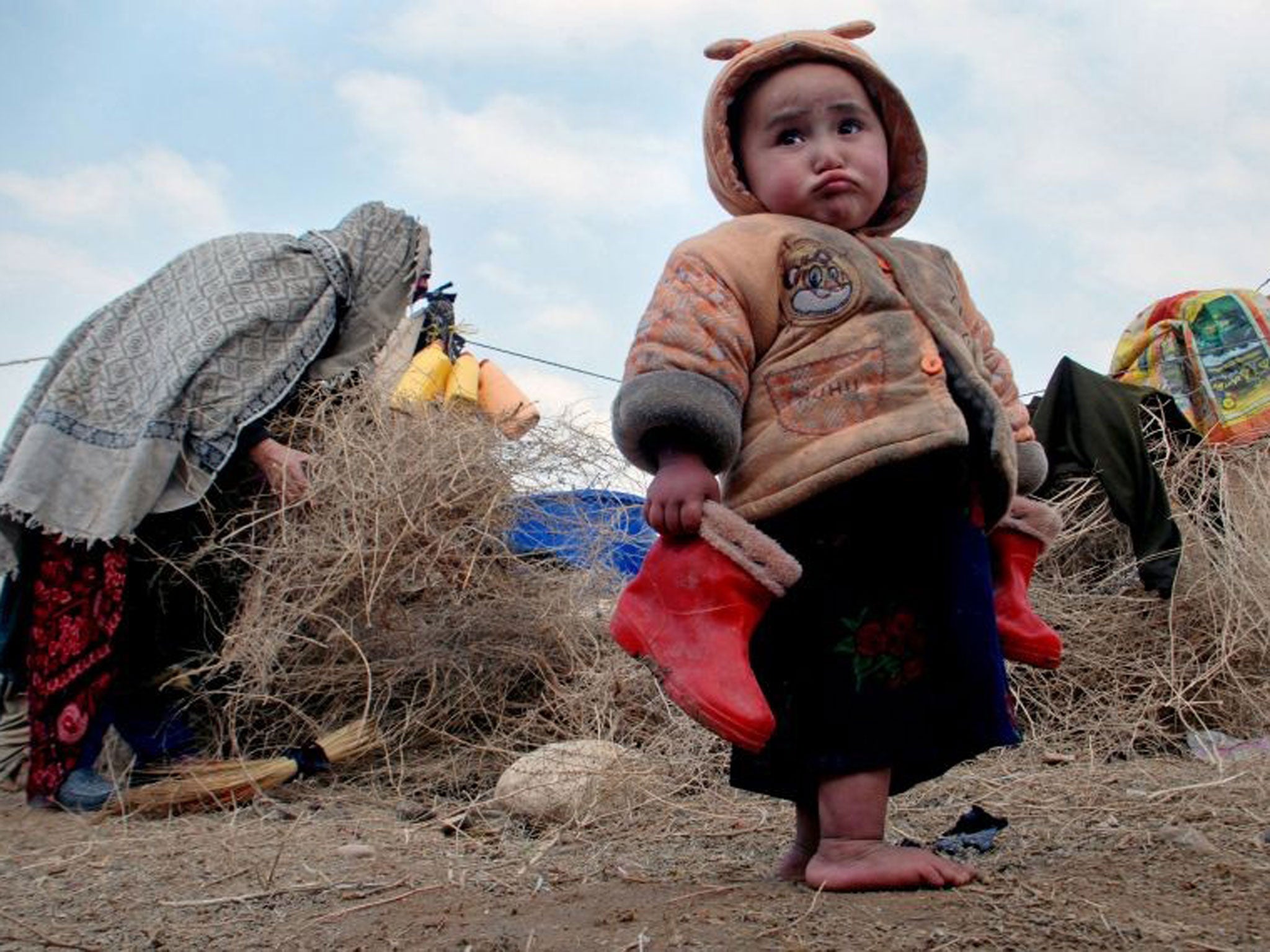 An Afghan child holds his boots in a camp for the internally displaced on the outskirts of Mazar-e Sharif, north of Kabul