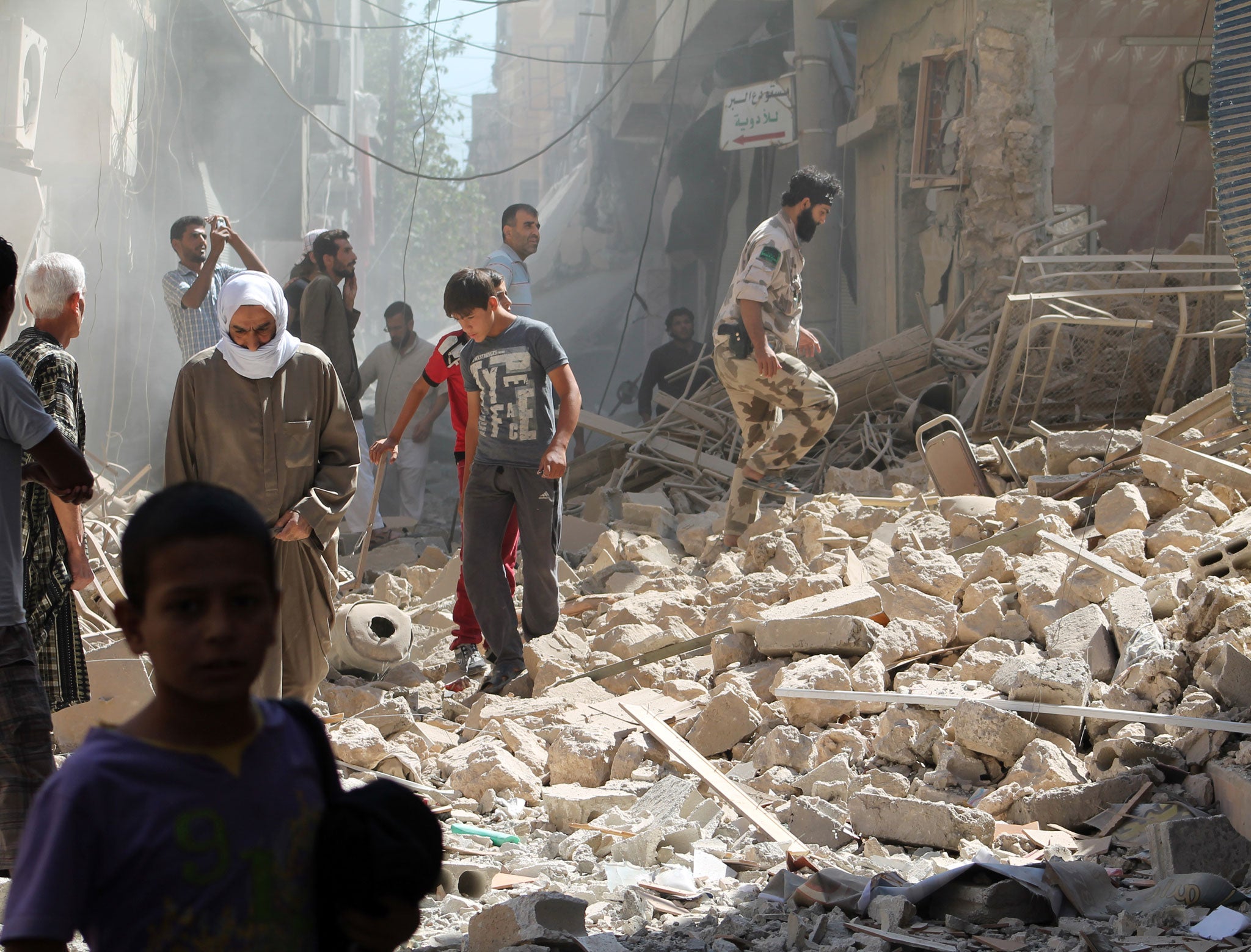 Residents of Syria's eastern town of Deir Ezzor walk past the debris of a building reportedly hit by a missile on September 26, 2013. The Syrian Observatory for Human Rights said that there was fighting between rebels and units of the jihadist Islamic State of Iraq and the Levant (ISIS) in Albu Kamal, with five people killed.