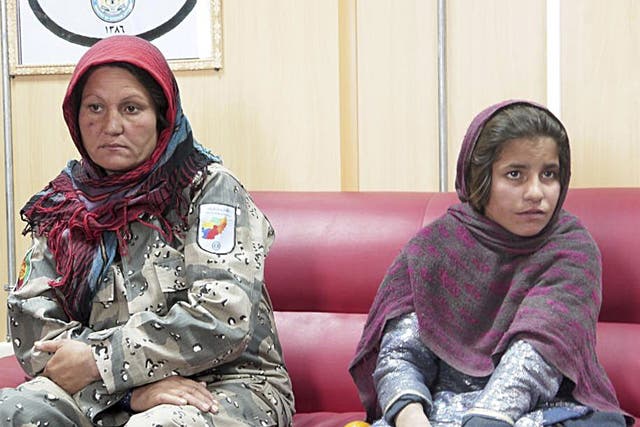Sphozmay, 10, who was about to be used by the Taliban as a suicide bomber, sits next to a police officer at a police office in Helmand province 