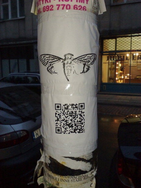 The cicada logo and an accompanying QR code are seen on a poster attached to a lampost in Warsaw.