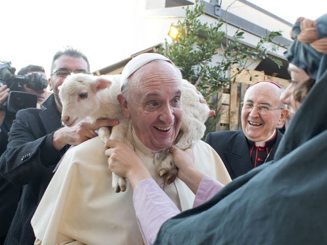 The pope has a lamb put around his neck by a woman dressed as a character from the nativity scene at Church of St Alfonso Maria dei Liguori in the outskirts of Rome