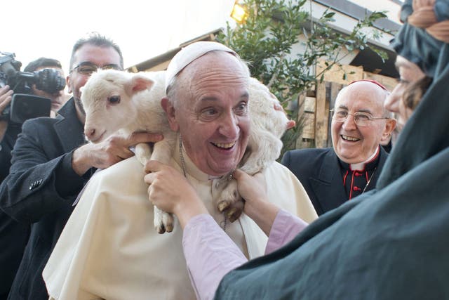 The pope has a lamb put around his neck by a woman dressed as a character from the nativity scene at Church of St Alfonso Maria dei Liguori in the outskirts of Rome