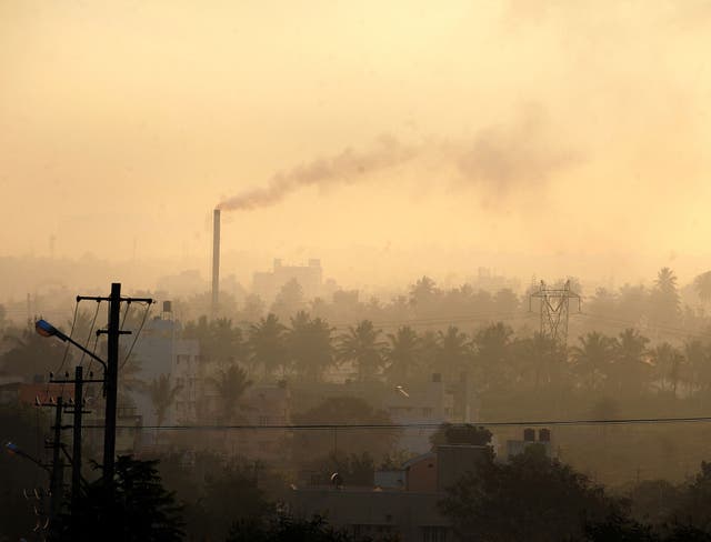 A factory chimney in a residential area emits smoke as haze casts a blanket over Bangalore