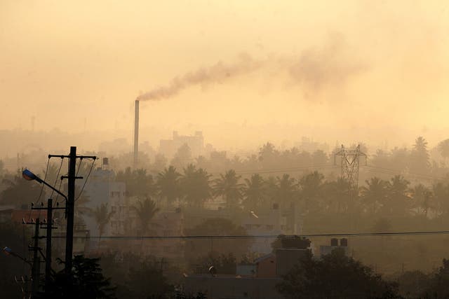 A factory chimney in a residential area emits smoke as haze casts a blanket over Bangalore