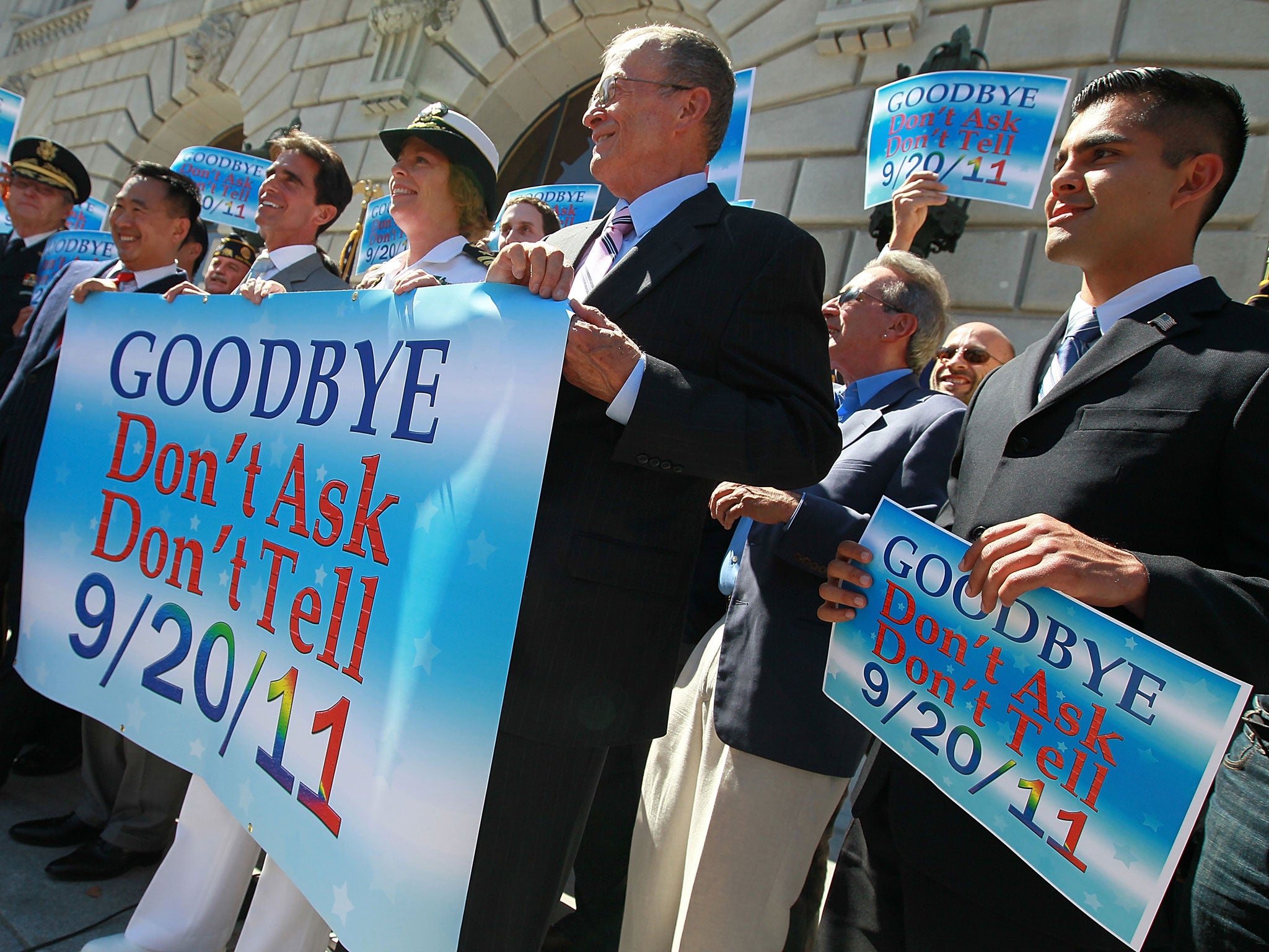 Local leaders and former members of the military hold a banner during a news conference marking the end of 'don't ask, don't tell' policy on September 20, 2011