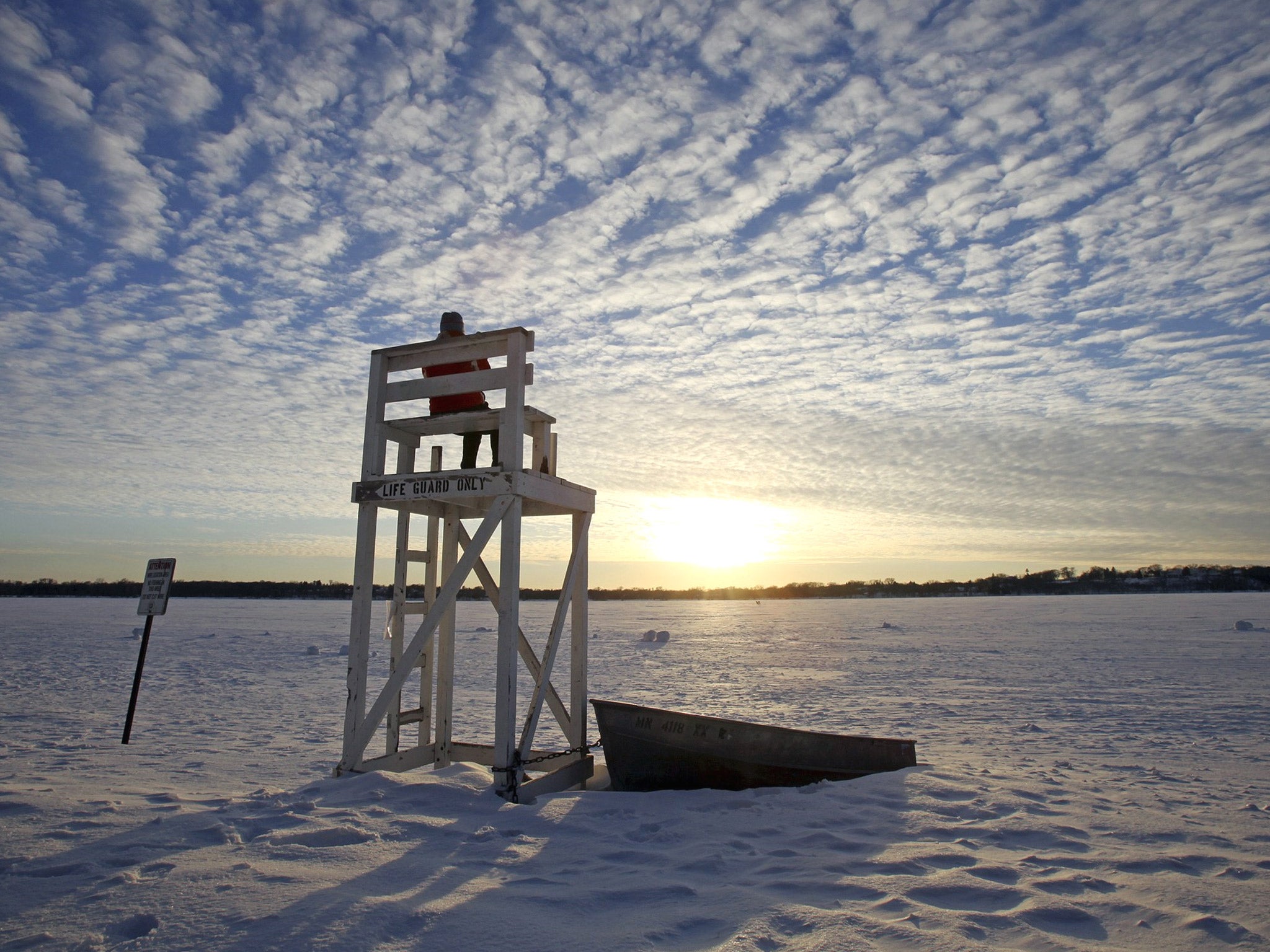 Lifeguard Jennifer Berry watches the sunset over a frozen Lake Calhoun in Minnesota during the cold snap