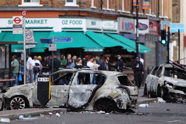 Burnt out cars lie in the road after riots on Tottenham High Road on August 7, 2011