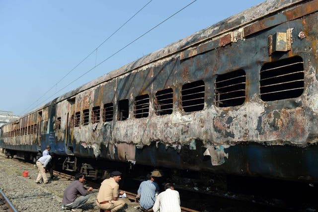 Indian railway and police officials inspect the burnt carriages of the long distance passenger train near Dahanu railway station