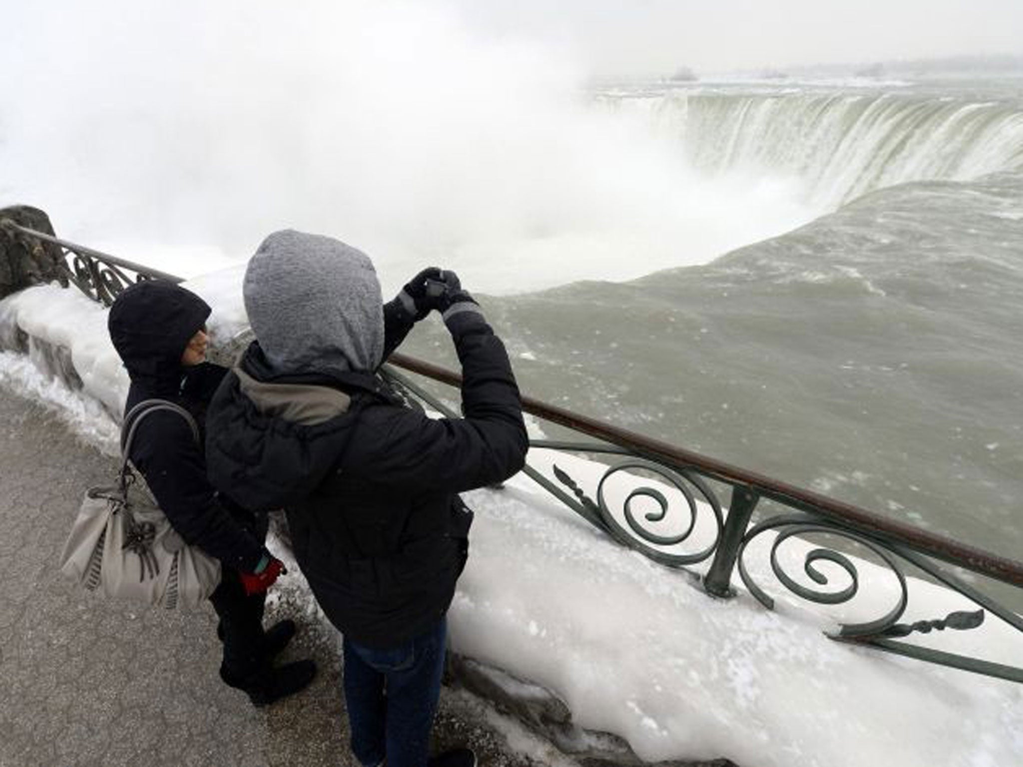 Visitors take pictures overlooking the falls in Niagara Falls in Ontario