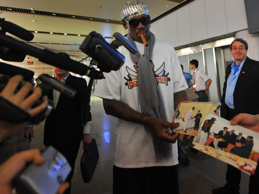 Former US basketball player Dennis Rodman shows pictures of him reportedly with North Korean leader Kim Jong-Un to media as he arrives at Beijing International Airport on September 7, 2013. Rodman returned to China from Pyongyang on September 7 after a fi