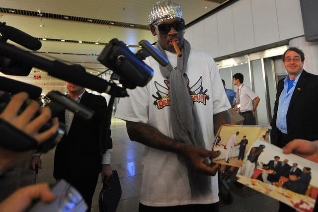 Former US basketball player Dennis Rodman shows pictures of him reportedly with North Korean leader Kim Jong-Un to media as he arrives at Beijing International Airport on September 7, 2013. Rodman returned to China from Pyongyang on September 7 after a fi
