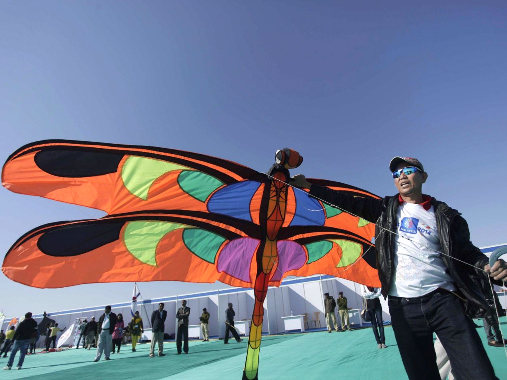 A man from Malaysia prepares to fly a kite during the International Kite Festival at white sand in the Rann of Kutch, a seasonal salt marsh located in the Thar Desert, in Dhordo, about 500 kilometers (311 miles) from Ahmadabad