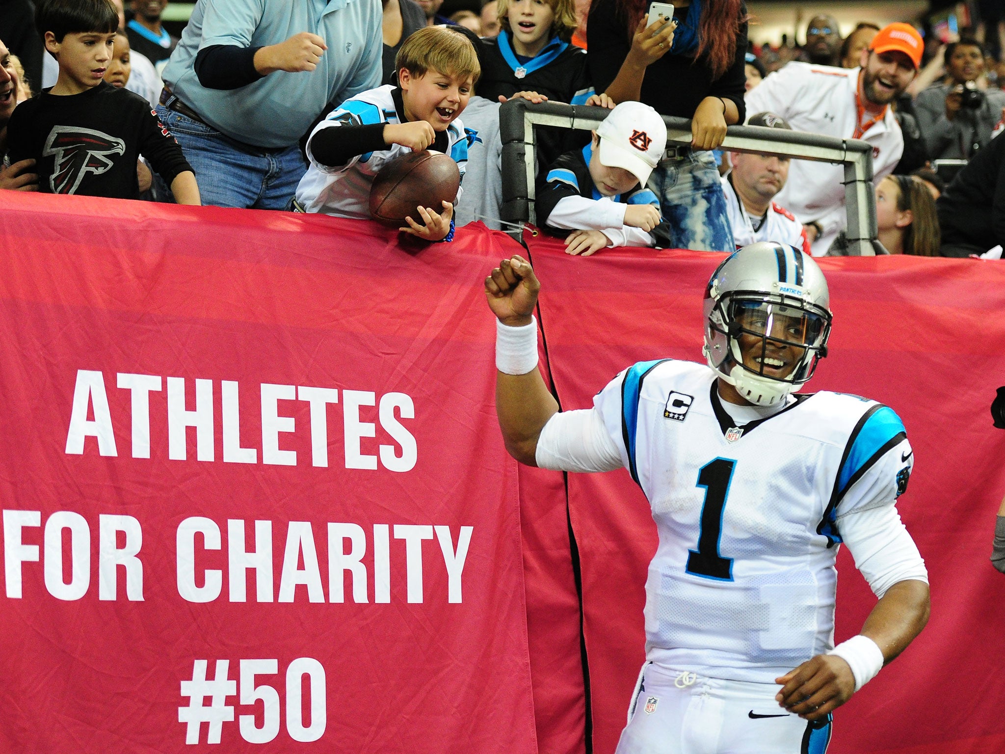 Carolina Panthers quarterback Cam Newton gives the ball to a young fan after running in a touchdown