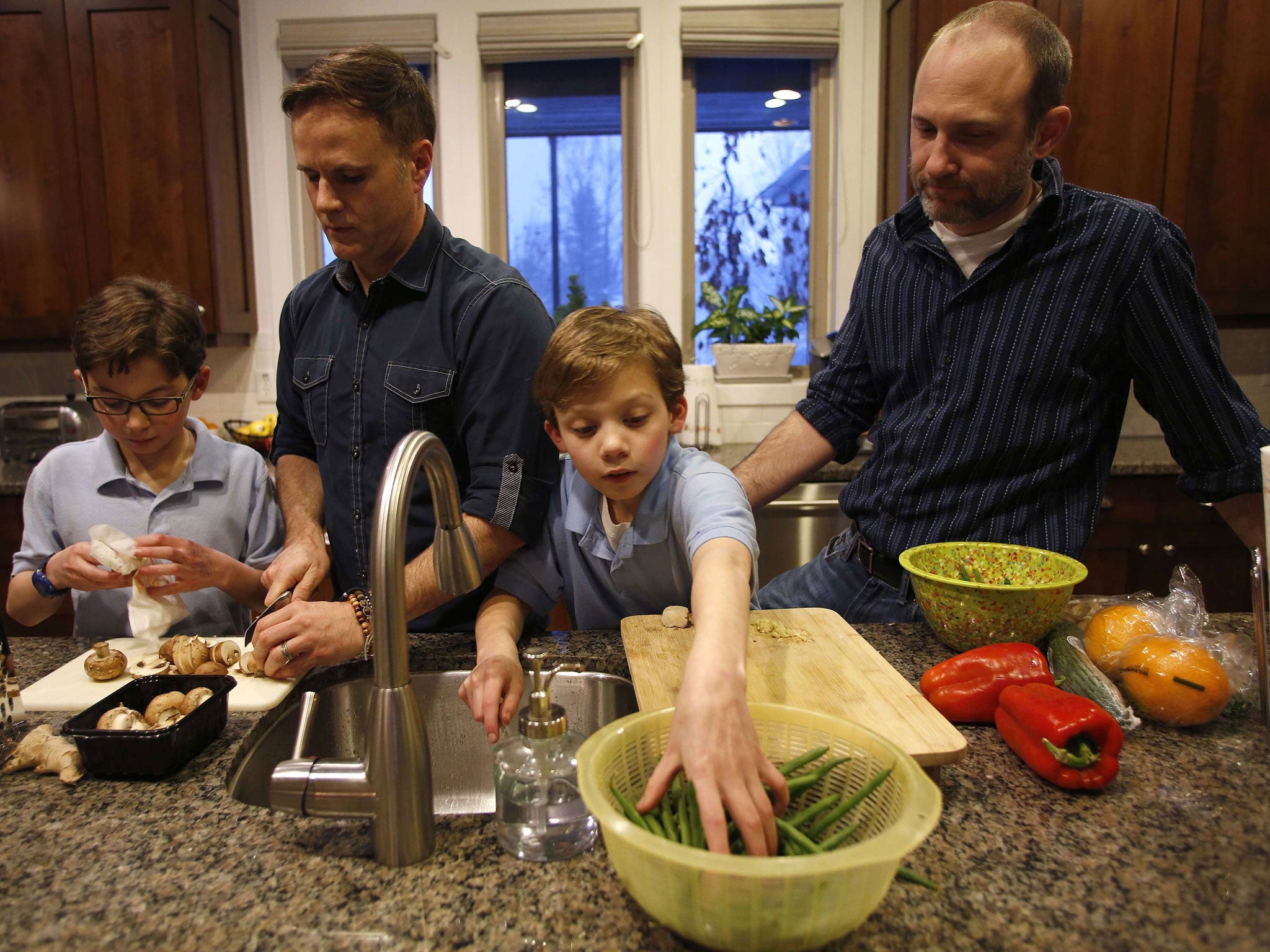 Paul Redd-Butterfield, second left, and his husband Tony Butterfield cook dinner with their adopted 11 year-old twin sons Lucas, left, and Liam at their home in Sandy, Utah. Paul and Tony were legally married in 2013. The US Government said it will recogn