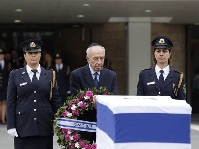 Israel's president Shimon Peres prepares to lay a wreath on the coffin of former prime minister Ariel Sharon