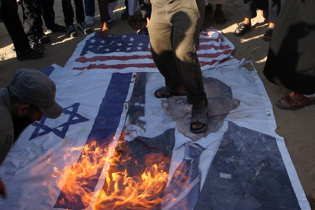 Palestinian Salafists walk on top of a picture of US President Barack Obama while burning Israeli and US flags during a protest against an amateur film mocking Islam in Rafah in the southern Gaza Strip on September 14, 2012