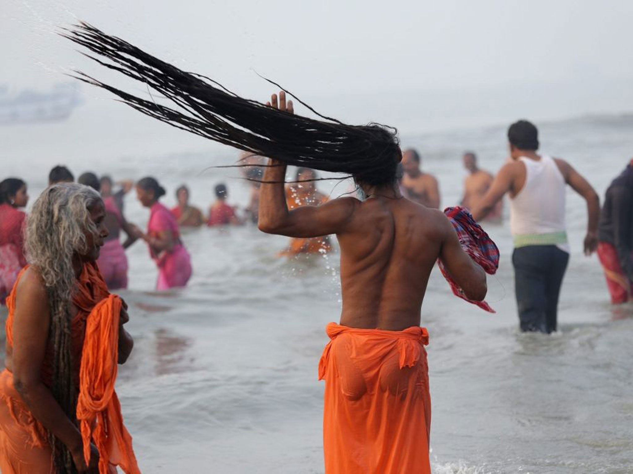 An Indian monk (C) takes a holy dip in the Bay of Bengal at Sagar Island 130km south of Calcutta