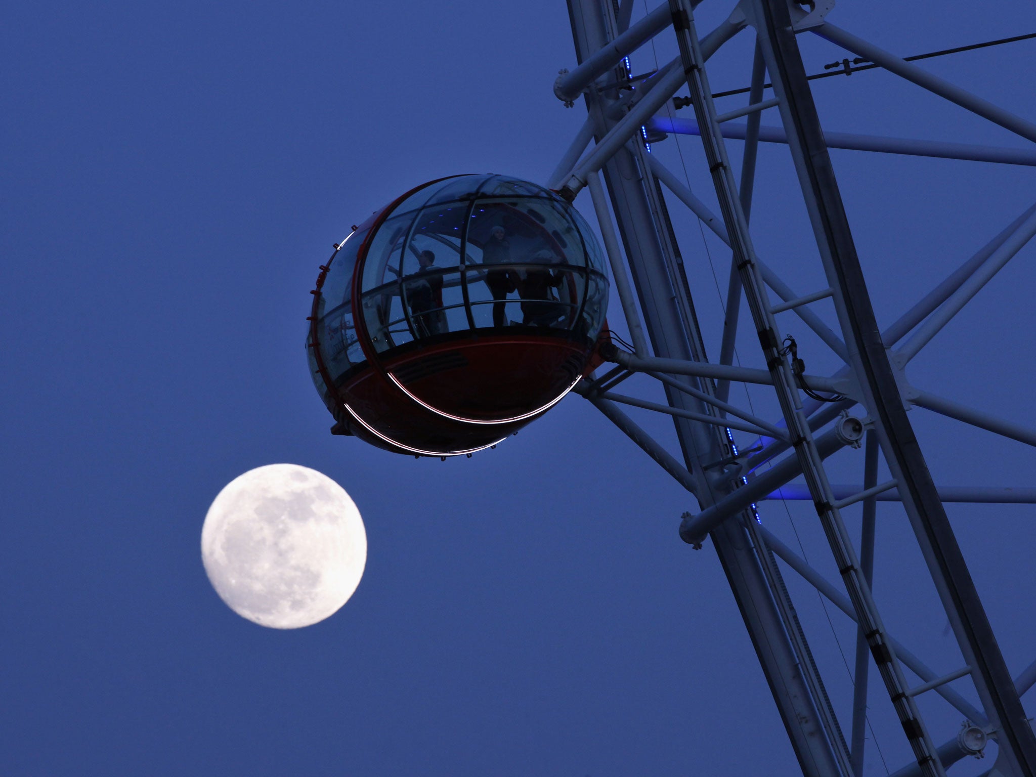 The moon rises behind the London Eye at twilight in 2012.
