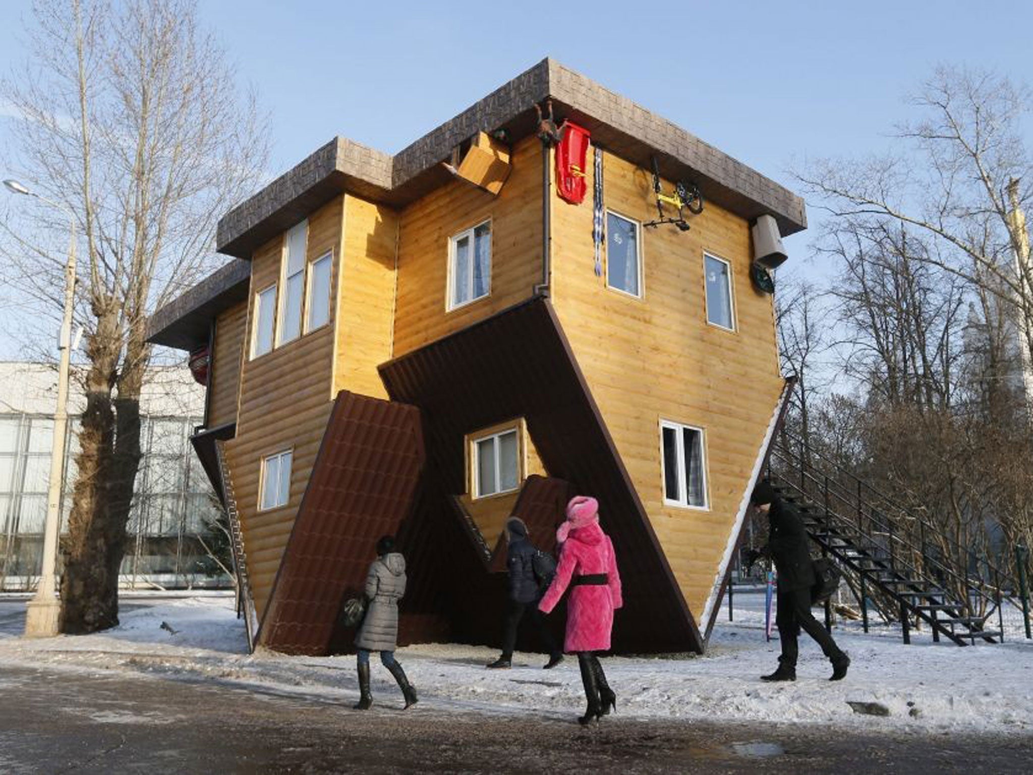 People look at an 'Upside Down House' attraction displayed at the VVTs the All-Russia Exhibition Center in Moscow