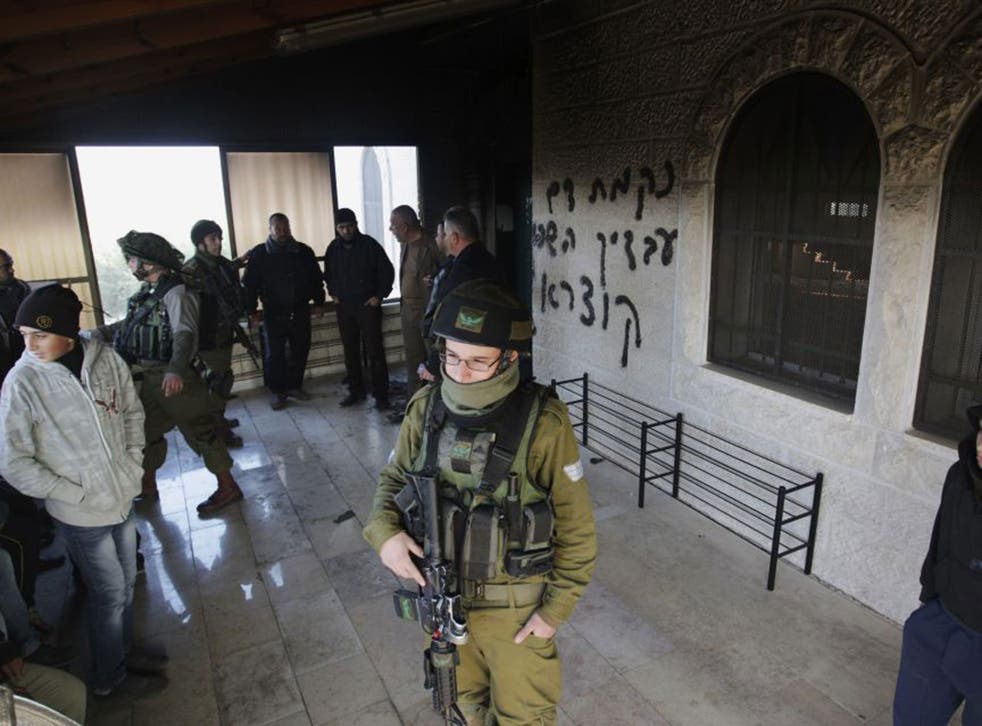Israeli soldiers on guard at a West Bank mosque damaged by settlers