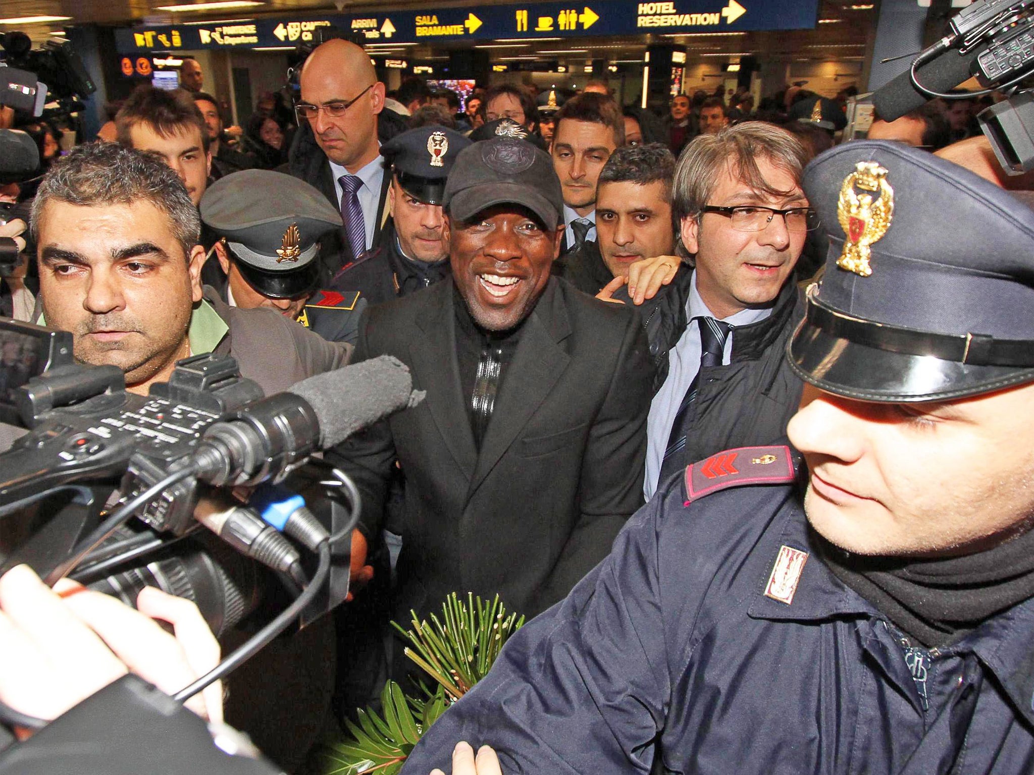 Clarence Seedorf (centre) is mobbed as he arrives at Linate Airport in Milan