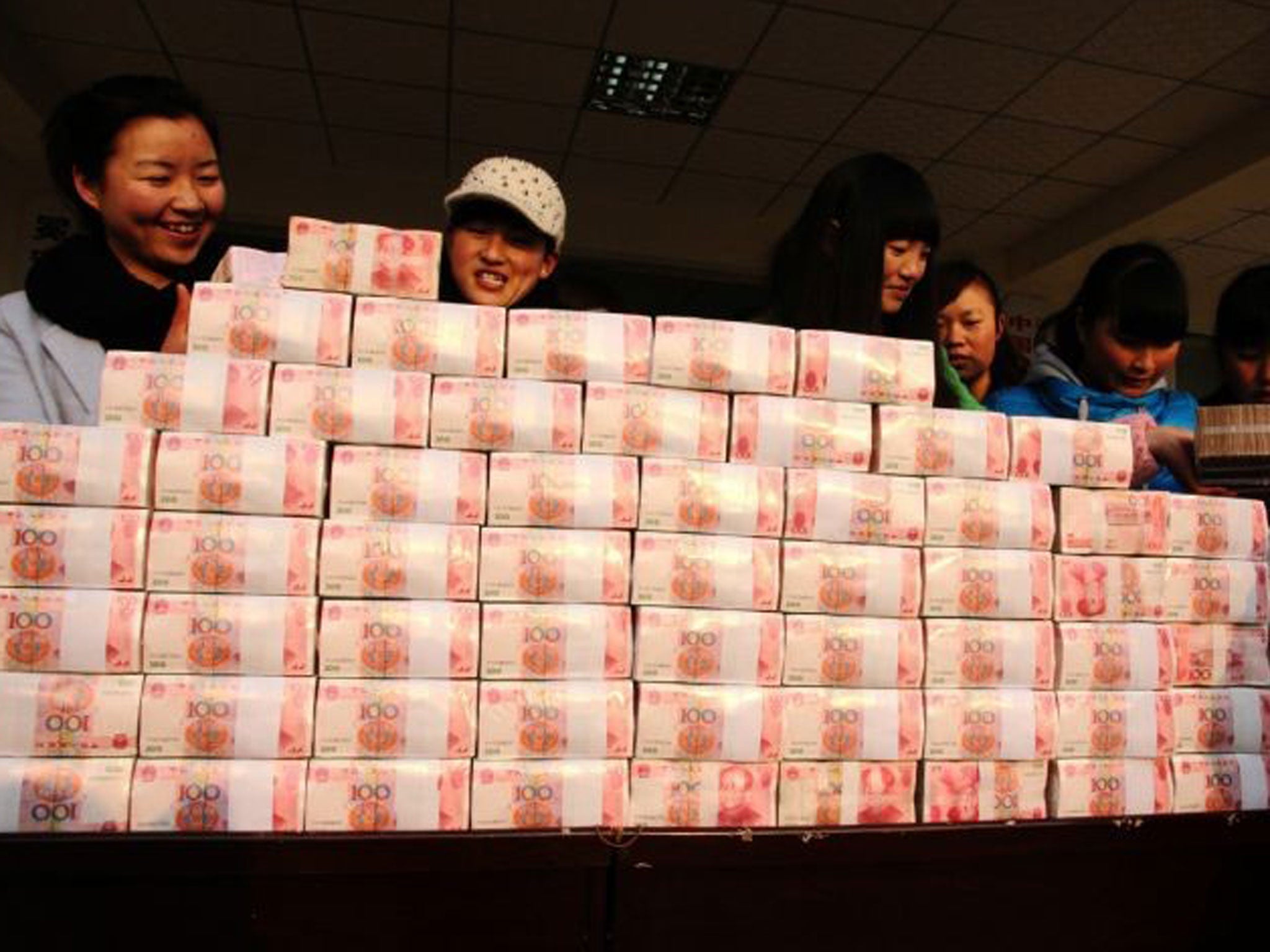 This picture taken on 14 January, 2014 shows villagers standing by a two-metre-long "money wall" built with cash for their year-end bonus at Jianshe village of Lianshan municipality, southwest China's Sichuan province.