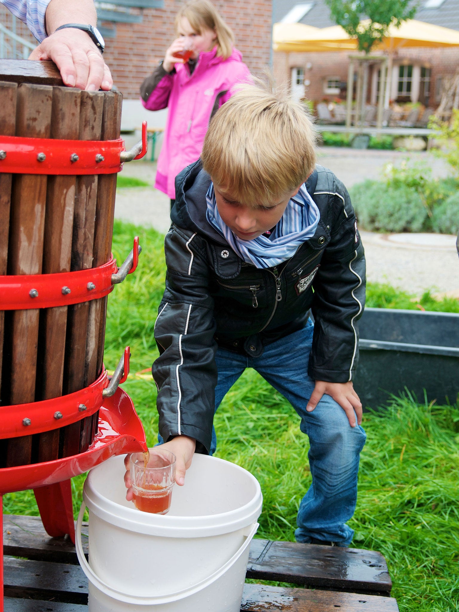 A boy pours himself a glass of apple juice from a community press (Alamy)