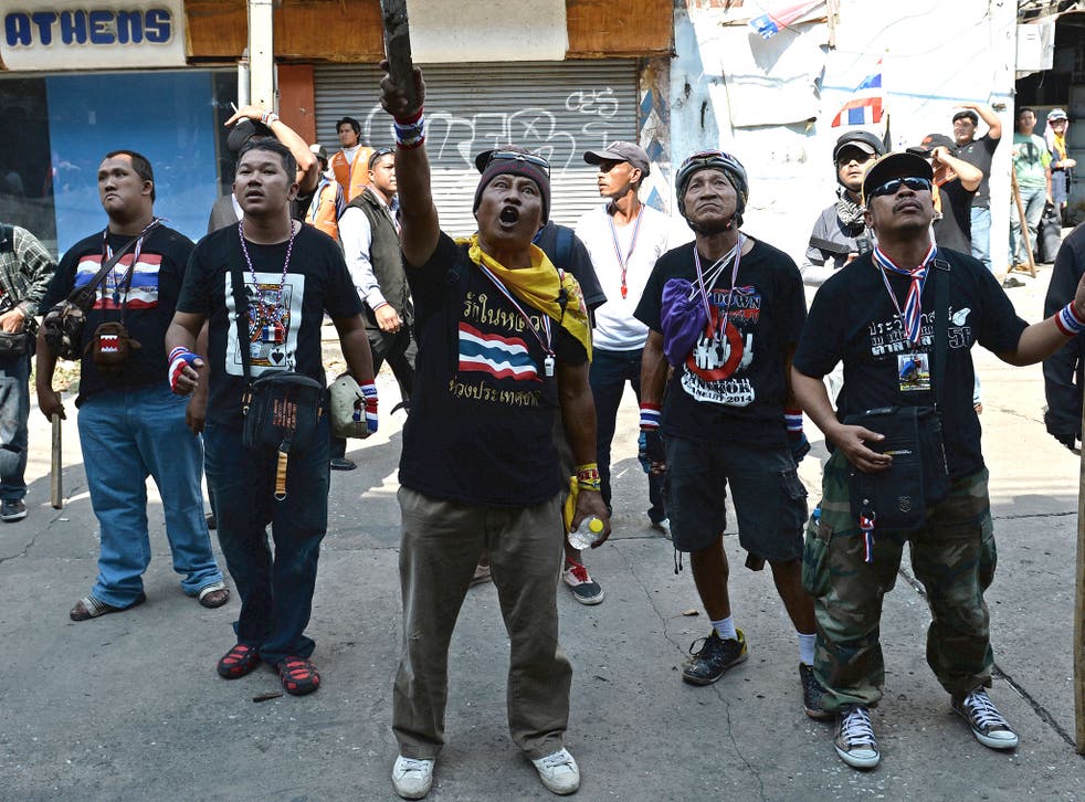 A Thai anti-government protester points a baton towards a building from where protesters suspected a bomb was thrown on an anti-government protest march in Bangkok on 17 January.