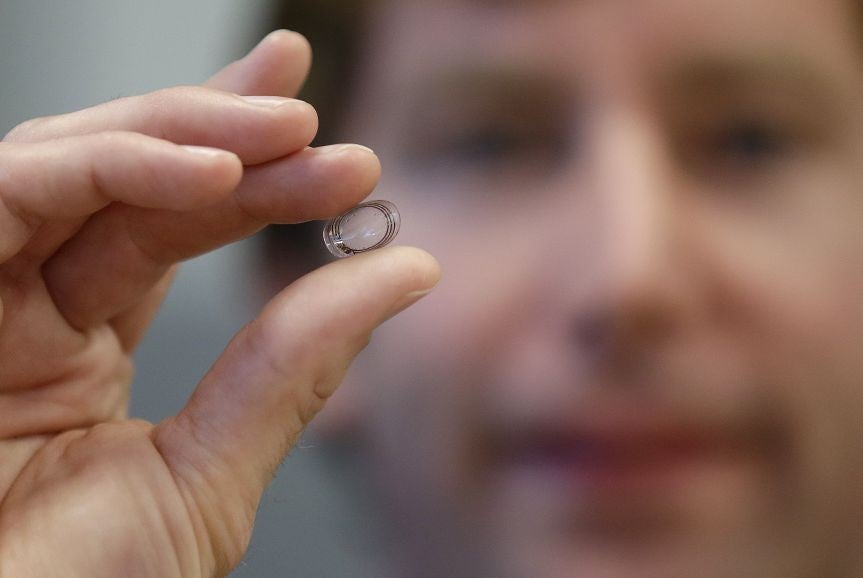 Brian Otis, project lead on the smart contact lens, holds the technology that he says is the smallest wireless glucose sensor ever made. Credit: AP.