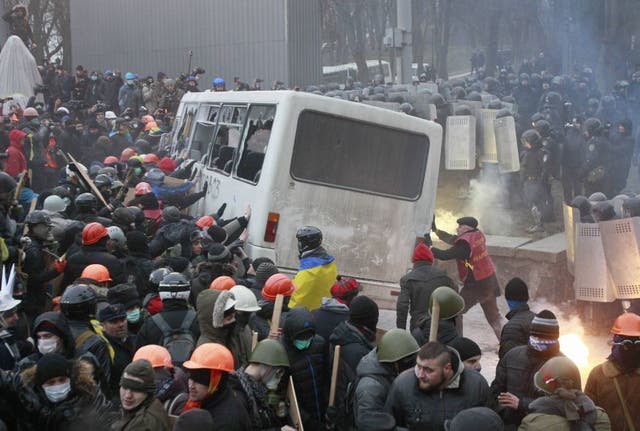 Protesters in hard hats attack a police van in Kiev
