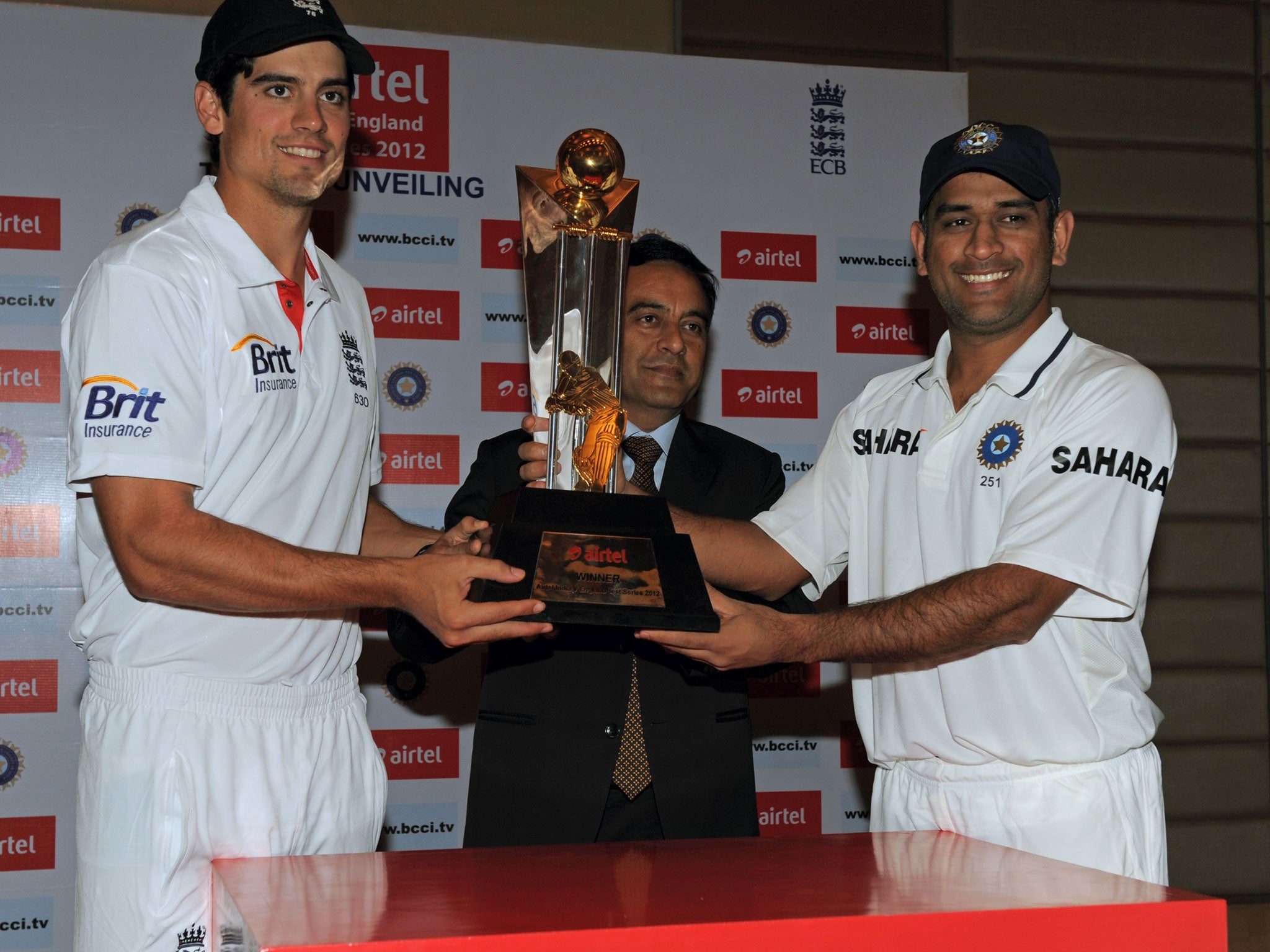 England cricket team captain Alastair Cook (left) and his Indian team counterpart Mahendra Singh Dhoni (right) pose with the championship trophy with Bharti Airtel Gujarat CEO Anant Arora (centre) in Ahmedabad in November 2012