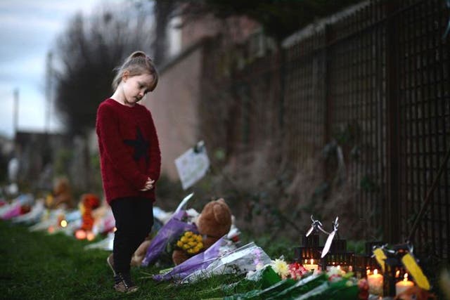 A young girl looks at flowers and candles laid by members of the public near to the house in Ferry Gait Crescent where 3 year-old  Mikaeel Kular was reported missing in Kirkcaldy