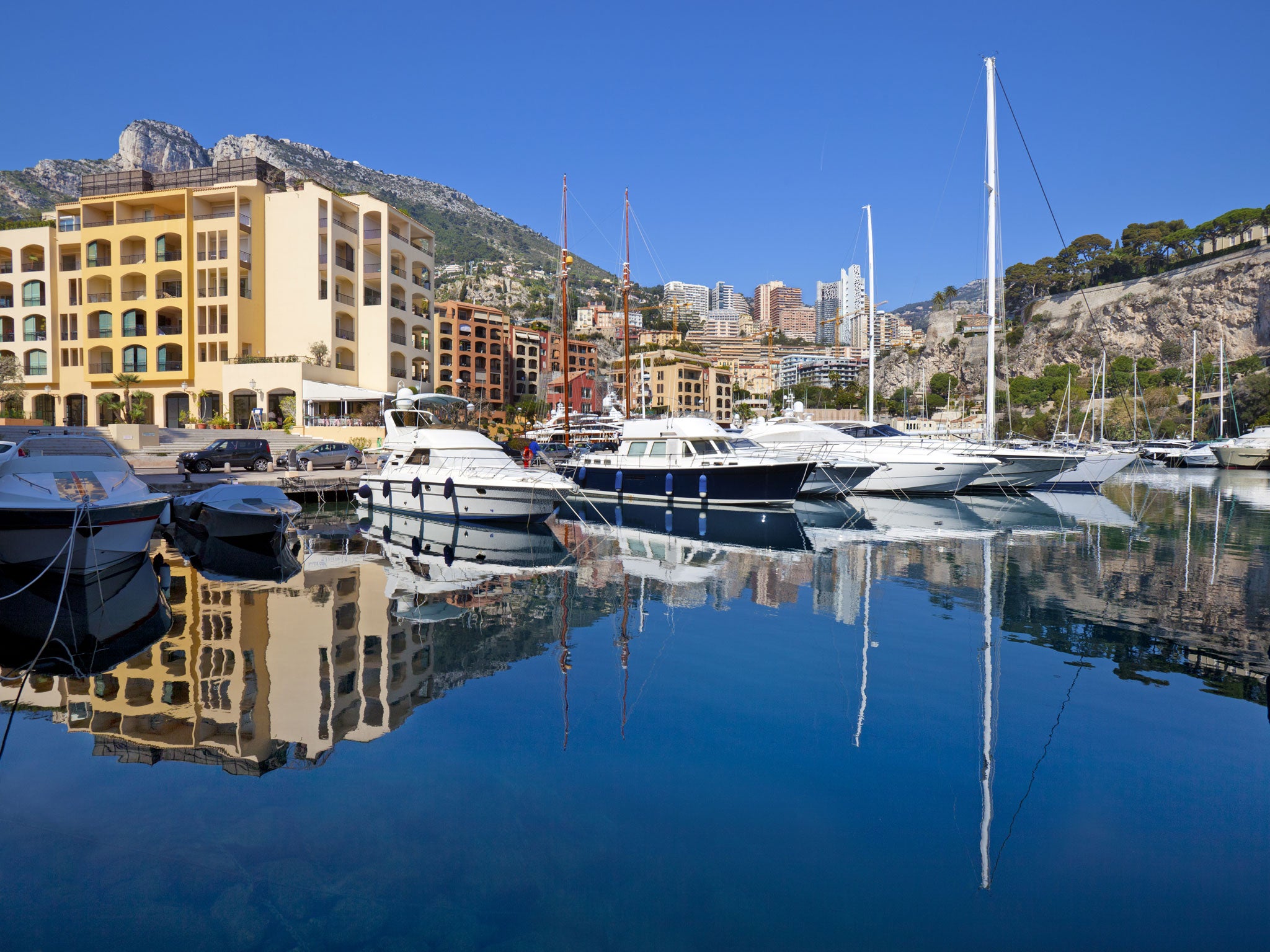 Luxury yachts and apartment buildings reflected in the calm waters of Fontvieille harbor, Monaco