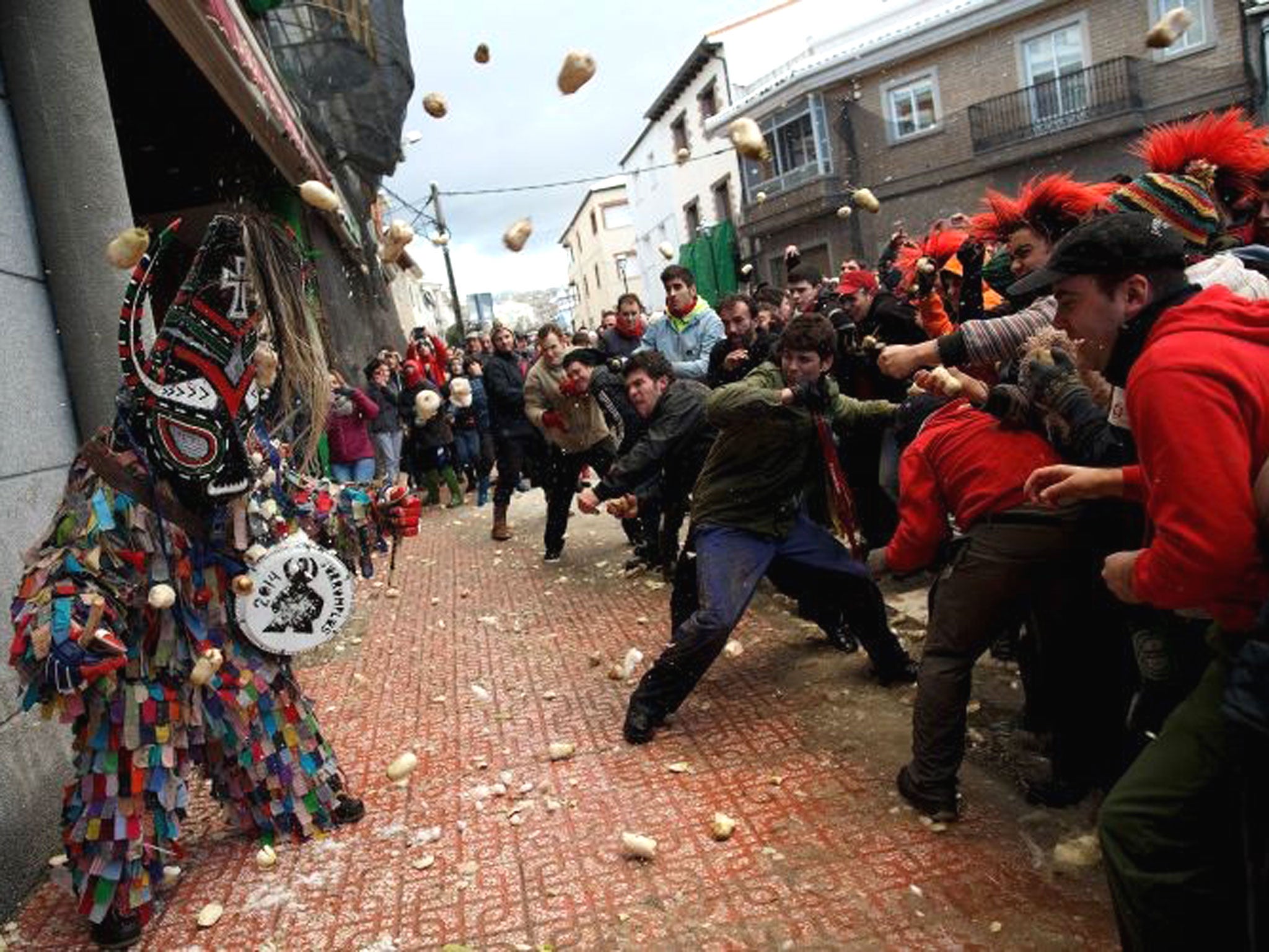 People throw turnips at the Jarramplas as he makes his way through the streets beating his drum during the Jarramplas Festival in Piornal