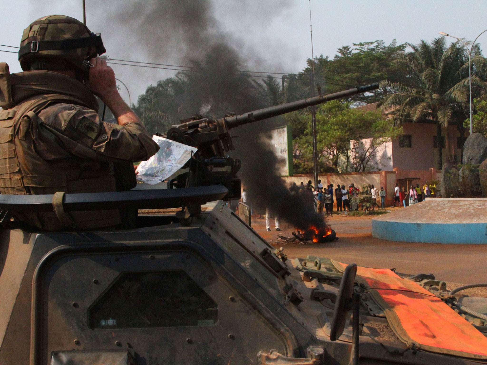 A French soldier looks on as the body of a lynched Muslim man is burned by a crowd, in Bangui; the EU has decided to send out troops to help stabilise the country
