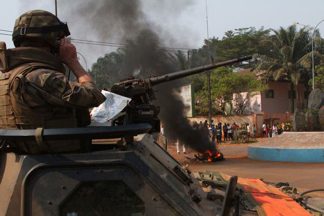 A French soldier looks on as the body of a lynched Muslim man is burned by a crowd, in Bangui; the EU has decided to send out troops to help stabilise the country
