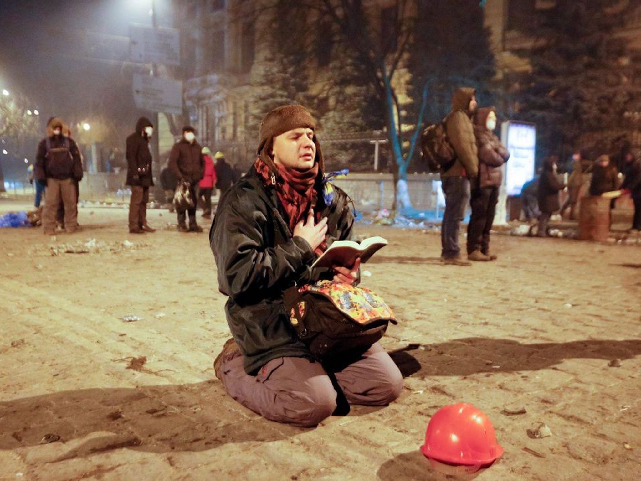 A protester prays as he holds an open Bible during an anti-government protest in downtown Kiev