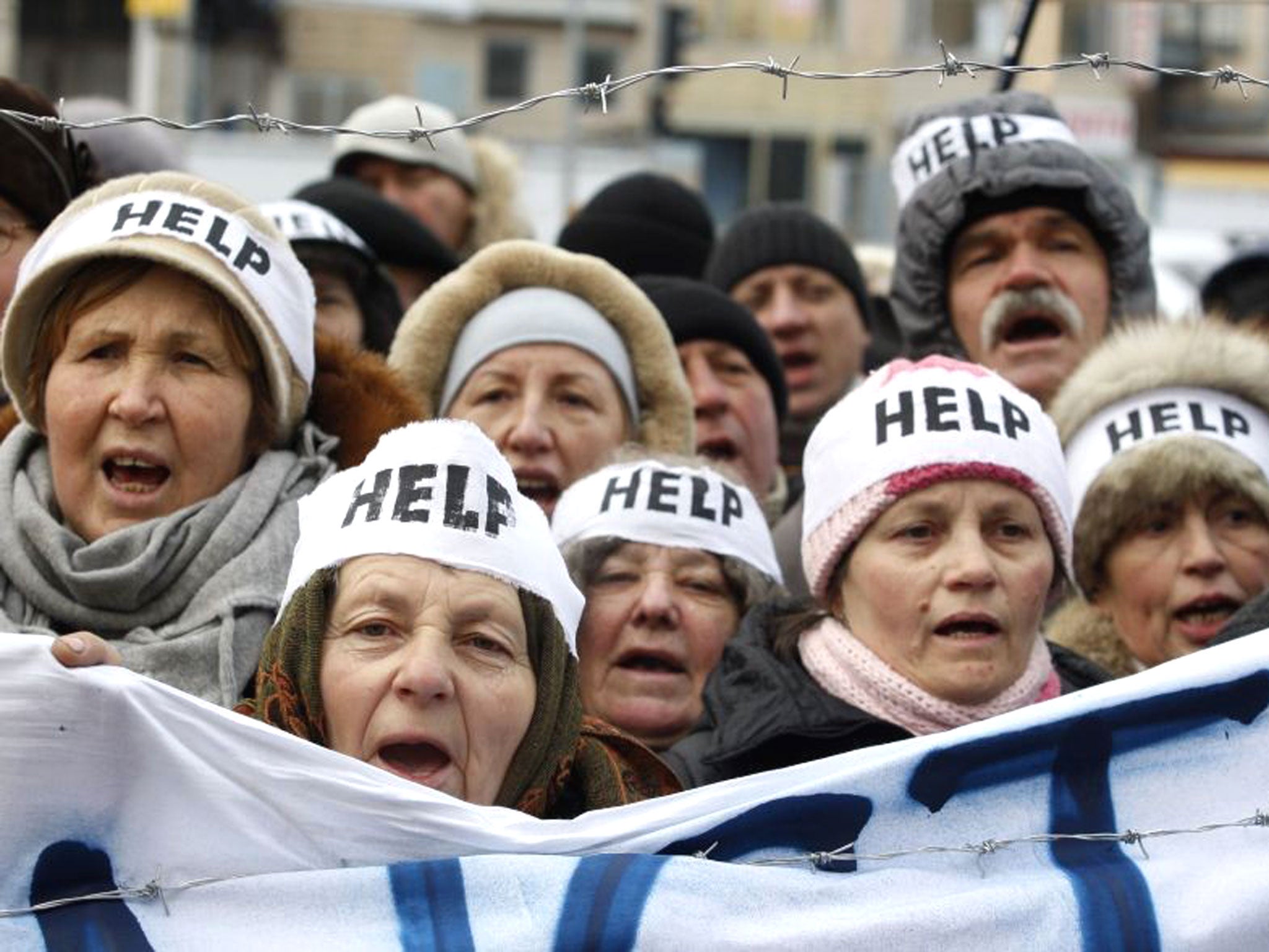 Protesters wearing headbands reading 'Help' shout slogans during an action entitled 'Impose sanctions - stop the violence' in front of the European Union delegation in Ukraine in Kiev.