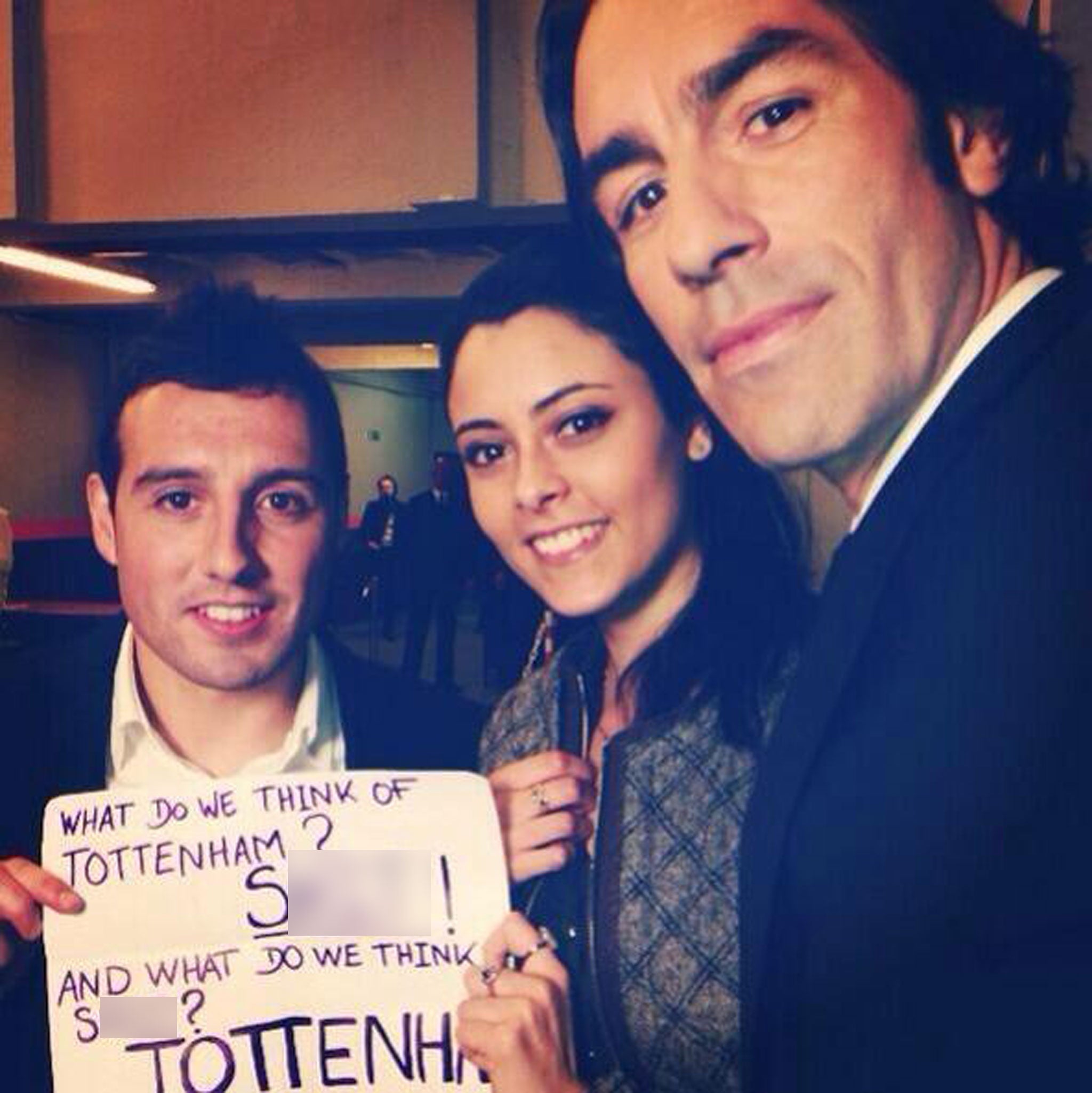 Current Arsenal midfielder Santi Cazorla and former player Robert Pires pose with a female fan holding an expletive-ridden chant aimed towards Tottenham supporters