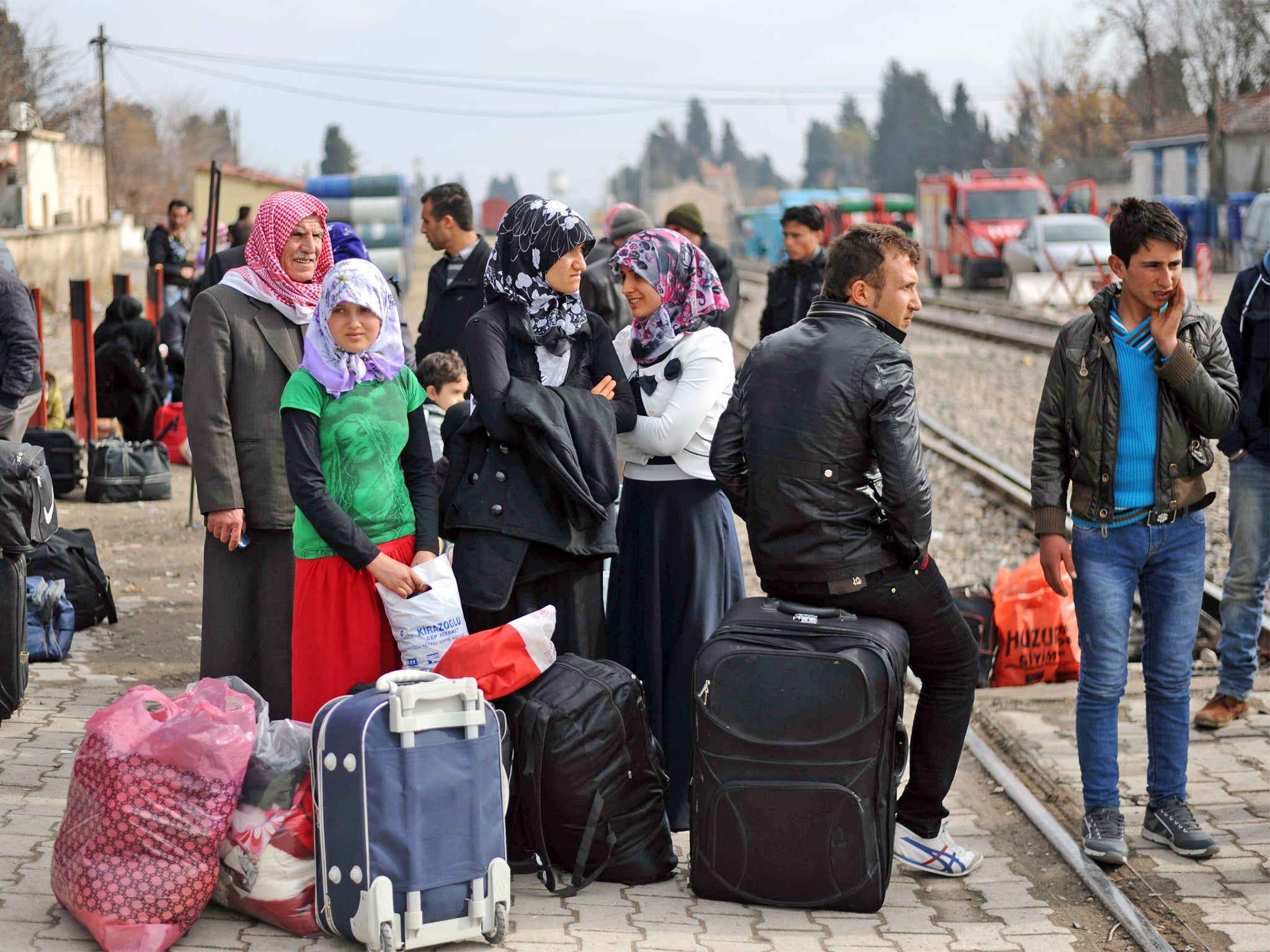 Syrian refugees wait with their belongings next to railway tracks after crossing the border into Turkey
