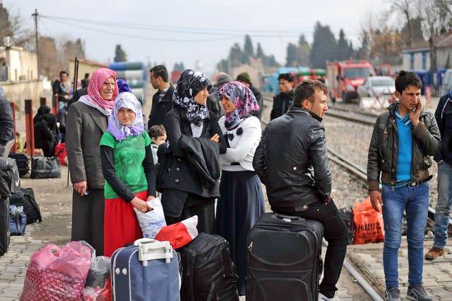 Syrian refugees wait with their belongings next to railway tracks after crossing the border into Turkey