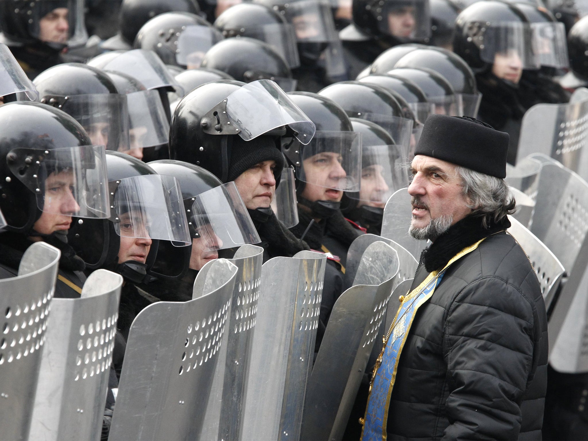 A clergyman opposes riot police in Kiev during a rally held by pro-European integration demonstrators.
