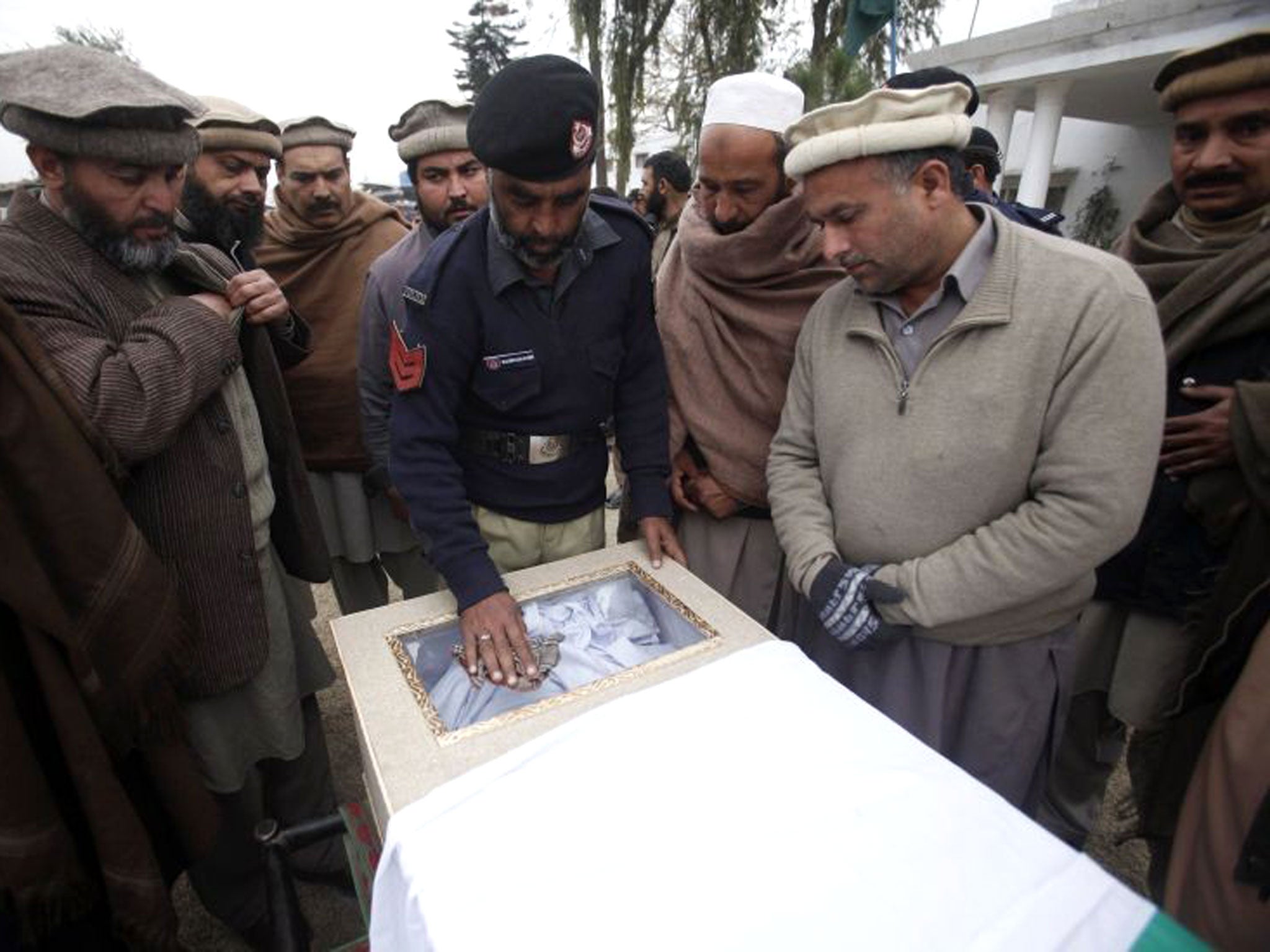 A policeman and relatives gather around the flag-draped casket of a policeman, who was killed in a bomb attack in Charsadda, on the outskirts of Peshawar